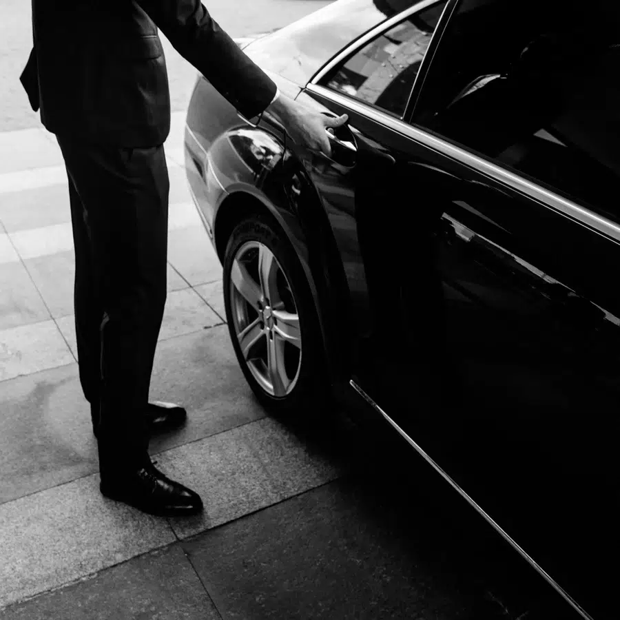 Homme ouvrant la porte d'une voiture de luxe