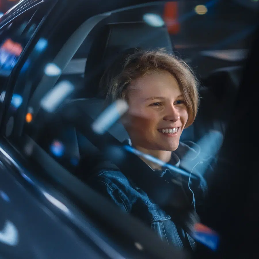 Jeune personne souriante dans une voiture la nuit